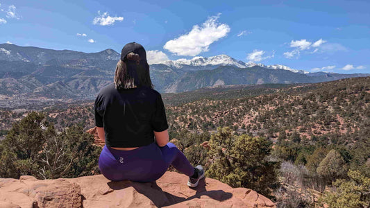 Woman in RECOSIVITY leggings sitting on a rock