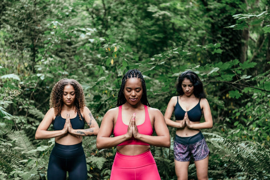 Three women meditating in a forest
